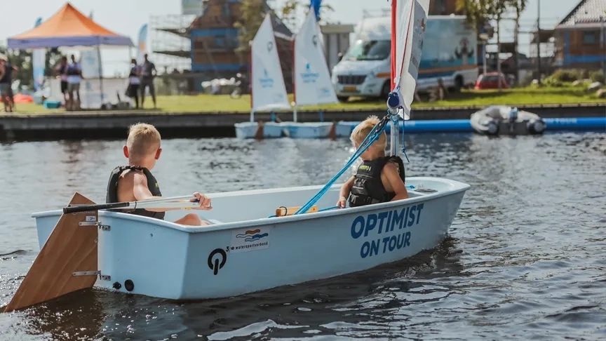 Twee jongetjes varen in een klein zeilbootje op het water