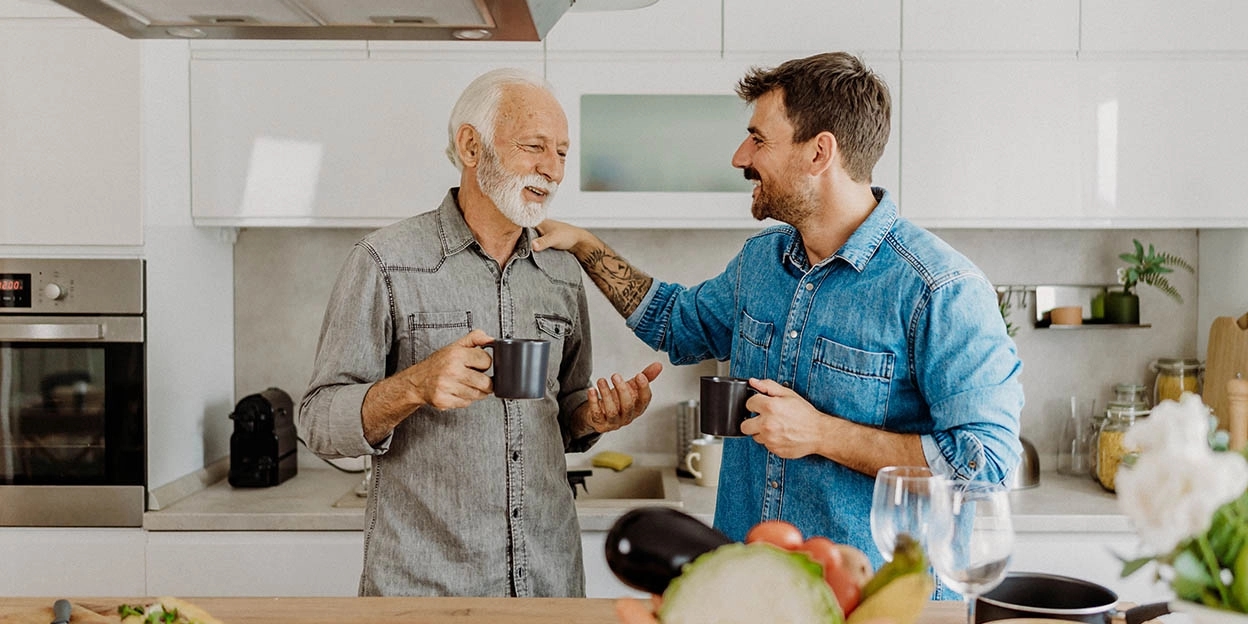 Zoon lacht vrolijk naar vader in de keuken