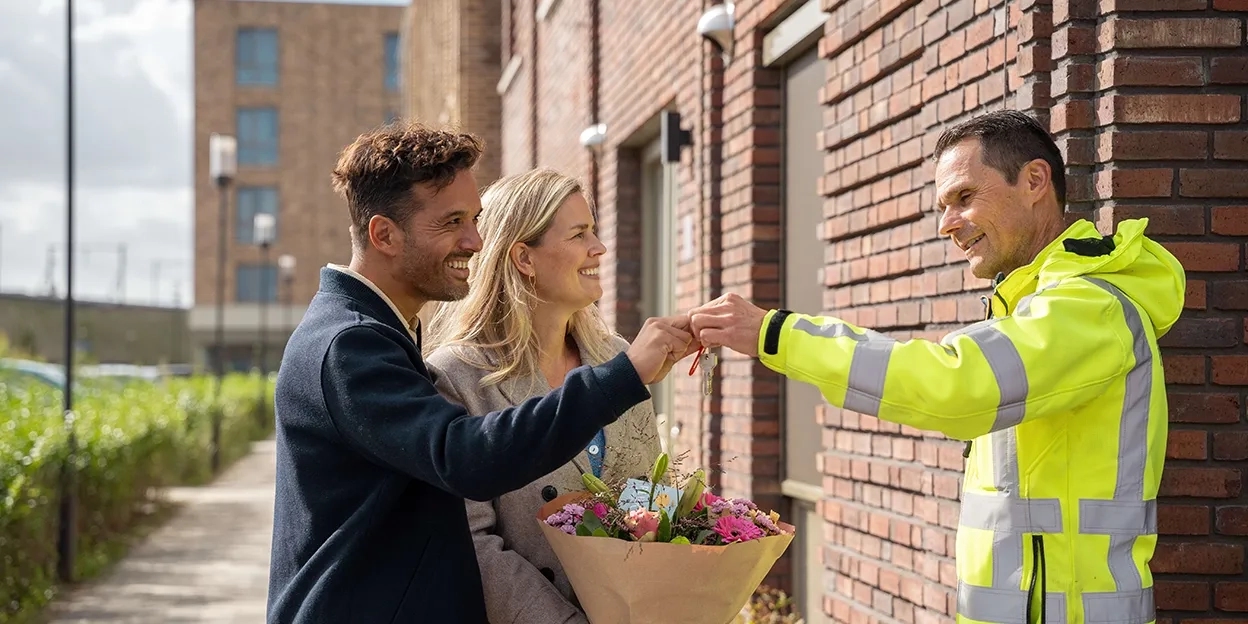 Man en vrouw krijgen de sleutels van hun nieuwe woning overhandigd