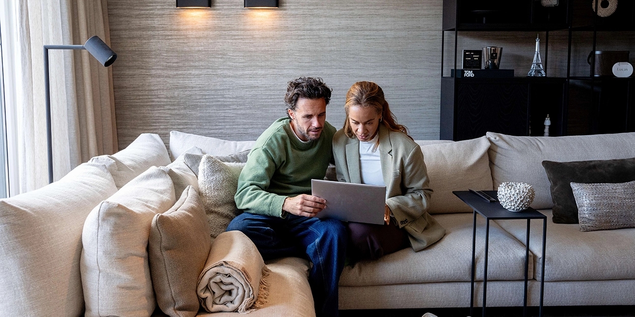 Jong stel zit op de bank met een laptop